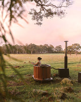 person bathing in a hot tub in farmland within a scenic setting