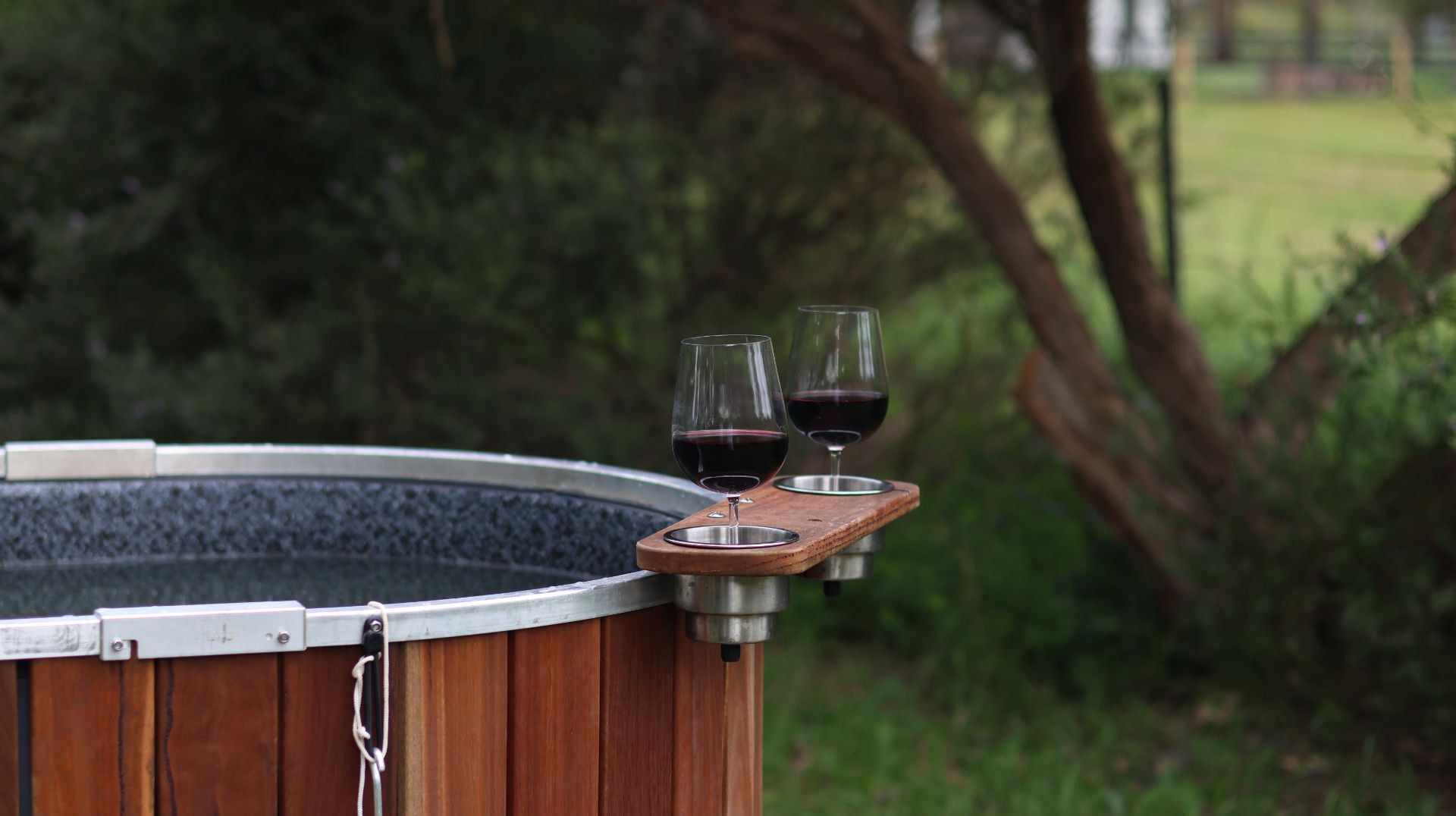 People enjoying a wood-fired hot tub spa bath surrounded by nature