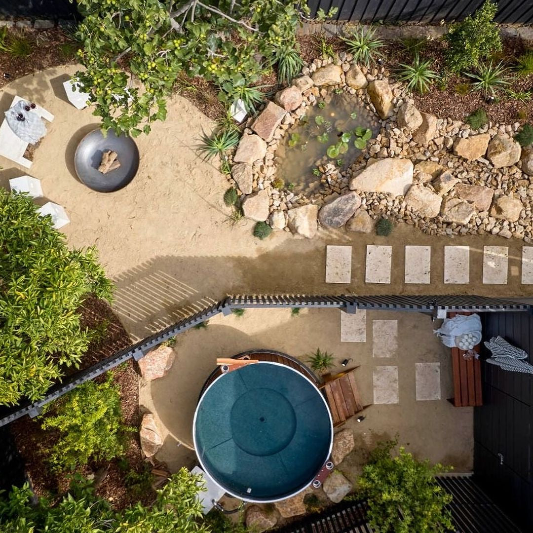 People relaxing in a wood-fired hot tub in a scenic outdoor setting