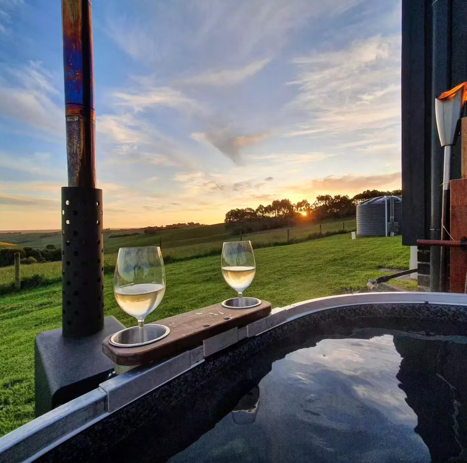 Wood-fired hot tub overlooking open paddock countryside